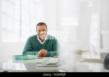 Geschäft. Ein Mann sitzt mit gefalteten Händen hinter einem Schreibtisch. Stockfoto