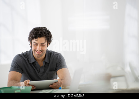 Geschäft. Eine leichte luftige Büroumgebung. Ein Mann sitzt mit einem digital-Tablette. Stockfoto