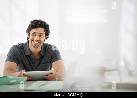 Geschäft. Eine leichte luftige Büroumgebung. Ein Mann sitzt mit einem digital-Tablette. Stockfoto