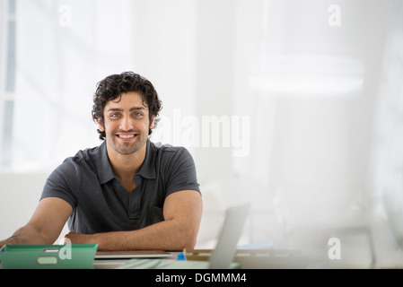 Geschäft. Ein Mann sitzt in einer entspannter Pose hinter einem Schreibtisch. Stockfoto