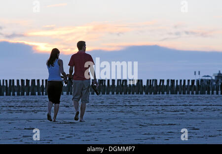 Junges Paar bei einem Spaziergang am Strand bei Sonnenuntergang, Zoutelande, Halbinsel Walcheren, der Provinz Zeeland, Niederlande, Benelux Stockfoto