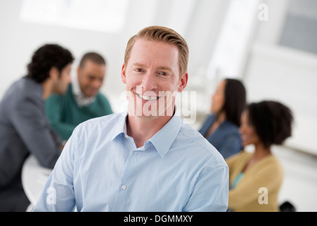 Business-Meeting. Eine Gruppe an einem Tisch sitzen. Ein Mann selbstbewusst Lächeln. Stockfoto