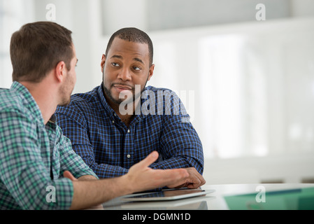 Büroeinrichtung. Zwei Männer an einem Tisch sitzen und mit einem digital-Tablette. Stockfoto