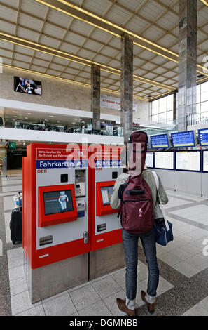 Junger Mann mit einer Gitarre auf dem Rücken, Kauf ein Zugticket am Fahrkartenautomat der ÖBB, Oesterreichische Bundesbahnen Stockfoto