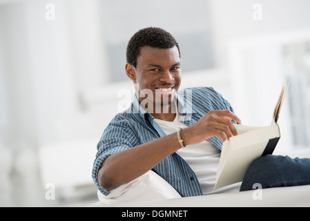 Ein helles weißes Zimmer Interieur. Ein Mann sitzt ein Buch zu lesen. Stockfoto