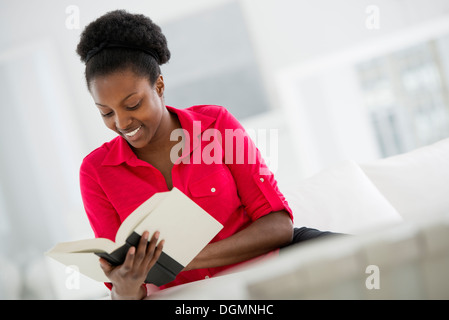 Ein helles weißes Zimmer Interieur. Sitzt eine Frau ein Buch zu lesen. Stockfoto