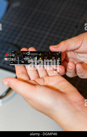 Des Kindes Hände halten ein elektronisches Bauteil mit Leuchtdioden, Gipfel IdeenParks 2012, Technologie und Bildung Stockfoto