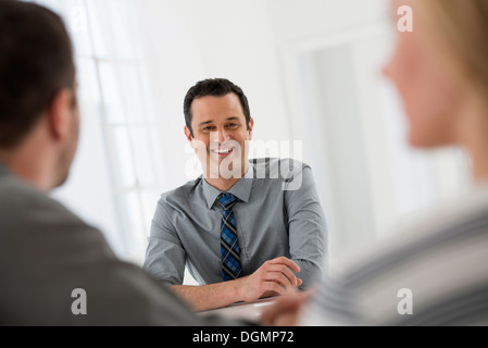 Büroeinrichtung. Drei Personen sitzen um einen Tisch bei einem Geschäftstreffen. Stockfoto