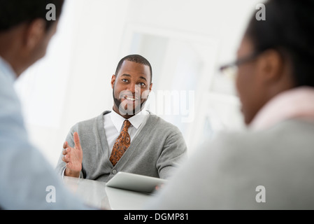 Büroeinrichtung. Drei Personen sitzen um einen Tisch bei einem Geschäftstreffen. Stockfoto