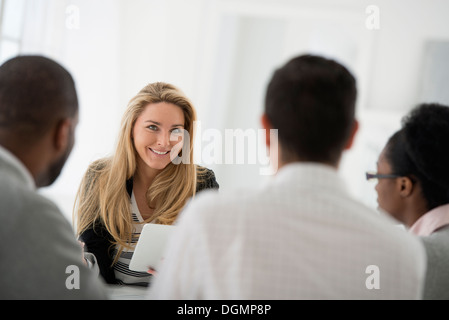 Büroeinrichtung. Eine Gruppe von vier Personen, zwei Männer und zwei Frauen an einem Tisch sitzen. Business-Meeting. Stockfoto