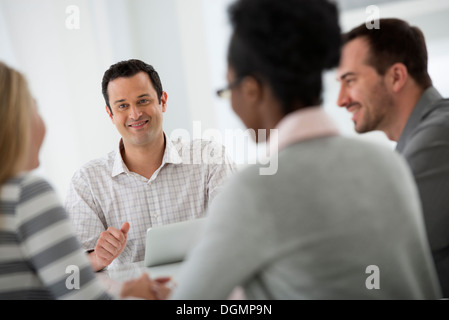 Büroeinrichtung. Eine Gruppe von vier Personen, zwei Männer und zwei Frauen an einem Tisch sitzen. Business-Meeting. Stockfoto