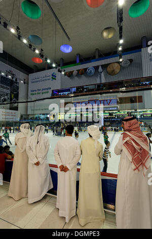 Araber, die traditionellen weißen Dischdascha tragen Roben beobachten Eisläufern, Dubai Ice Rink, Dubai Mall, Vereinigte Arabische Emirate Stockfoto