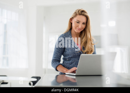 Büroeinrichtung. Eine Frau sitzt an einem Tisch mit einem digitalen Tablet. Stockfoto