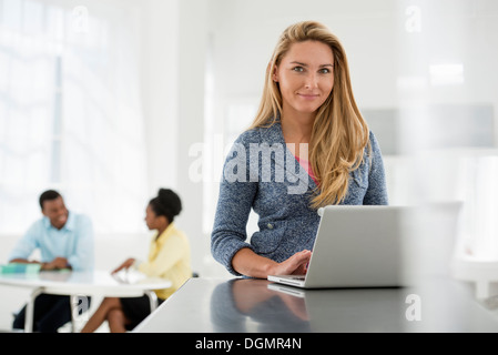 Büroeinrichtung. Eine Frau sitzt an einem Tisch mit einem digitalen Tablet. Stockfoto