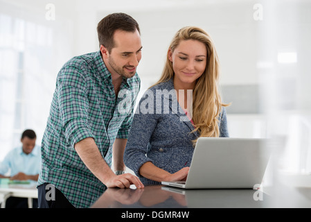 Büroeinrichtung. Ein paar an einem Tisch, einem Computer-Bildschirm betrachten. Stockfoto