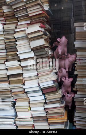 Gestapelte Bücher und dekorative Schweine in einem Schaufenster, skurrile Buchhandlung, historische Einkaufspassage, Passage Jouffroy Stockfoto