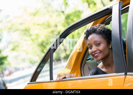 Eine Frau aus dem hinteren Beifahrersitz ein yellow Cab. Stockfoto