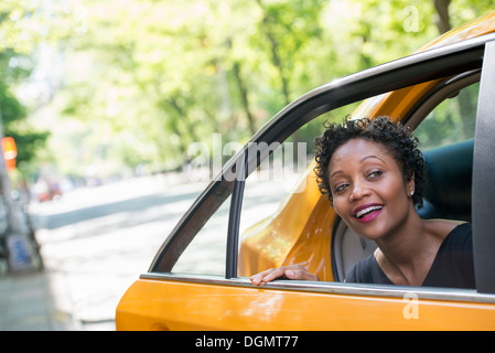 Eine Frau aus dem hinteren Beifahrersitz ein yellow Cab. Stockfoto