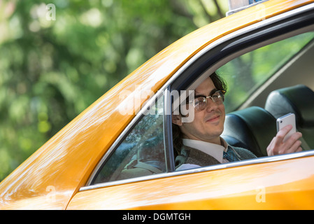 Leben in der Stadt. Menschen in Bewegung. Ein junger Mann auf dem Rücksitz eines Taxis. Stockfoto