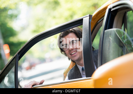 Leben in der Stadt. Menschen in Bewegung. Ein junger Mann auf dem Rücksitz eines Taxis. Stockfoto