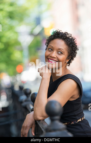 Menschen in Bewegung. Eine Frau in einem schwarzen Kleid auf einer Stadtstraße. Stockfoto