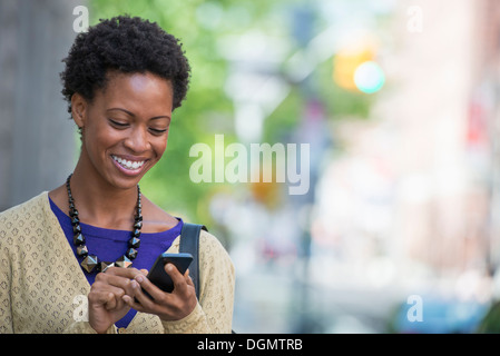 Stadt. Eine Frau in einem lila Kleid überprüfen ihr Smartphone. Stockfoto