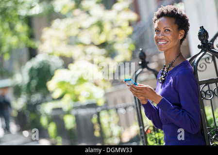 Stadt. Eine Frau in einem lila Kleid überprüfen ihr Smartphone. Stockfoto