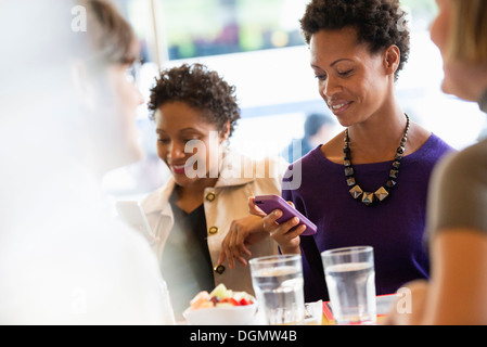 Leben in der Stadt. Eine Gruppe von Menschen in einem Café, überprüfen ihre Smartphones. Stockfoto