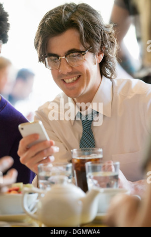 Leben in der Stadt. Eine Gruppe von Menschen in einem Café, überprüfen ihre Smartphones. Stockfoto