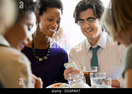 Leben in der Stadt. Eine Gruppe von Menschen in einem Café, überprüfen ihre Smartphones. Stockfoto