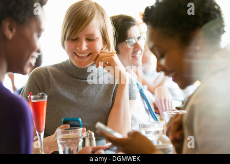 Leben in der Stadt. Eine Gruppe von Menschen in einem Café, überprüfen ihre Smartphones. Stockfoto