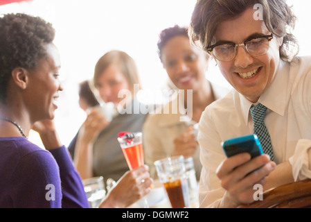 Leben in der Stadt. Eine Gruppe von Menschen in einem Café, überprüfen ihre Smartphones. Stockfoto