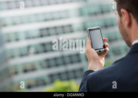 Stadt. Ein Mann im Anzug seine Nachrichten auf seinem Smartphone. Stockfoto