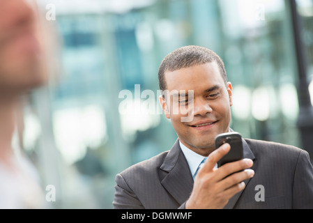 Stadt. Ein Mann im Anzug seine Nachrichten auf seinem Smartphone. Stockfoto