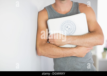 Sportlichen Mann hält eine Skala Wand gelehnt Stockfoto