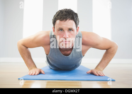 Hübscher sportlicher Mann tun Push ups auf blauen Matte Stockfoto