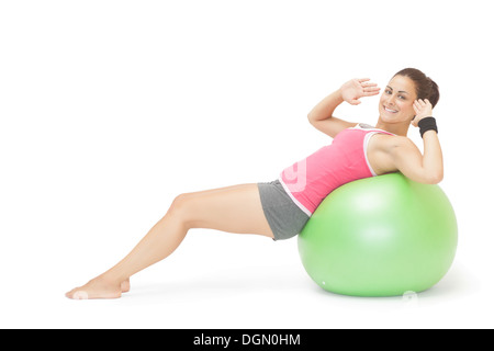 Lächelnd sportliche Brünette macht Sit-Ups auf Gymnastikball Stockfoto