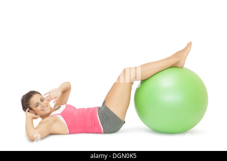 Lächelnd sportliche Brünette macht Sit-Ups mit Gymnastikball Stockfoto