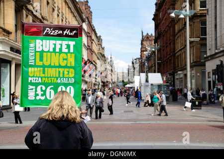 Eine Frau, die eine Anzeige für ein Pizza Hut Restaurant in einer Straße im Stadtzentrum von Glasgow, Schottland, Großbritannien, hält Stockfoto