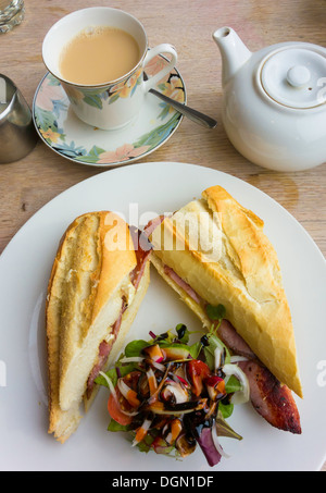 Gute Mittagsimbiss Brie und Speck sandwich in französisches Brot mit gemischtem Salat und eine Tasse Tee Stockfoto