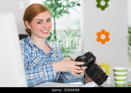 Glückliche Fotograf sitzt an ihrem Schreibtisch, halten Sie ihre Kamera Stockfoto