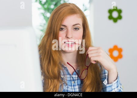 Schöne rothaarige sitzt an ihrem Schreibtisch in die Kamera Lächeln Stockfoto