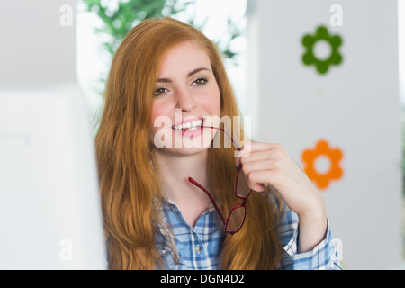 Schöne rothaarige sitzt an ihrem Schreibtisch und lächelnd Stockfoto