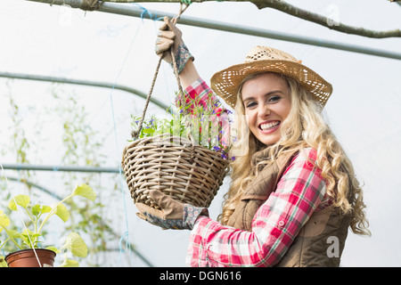 Hübsche Blondine zeigt eine hängende Blumenkorb Stockfoto