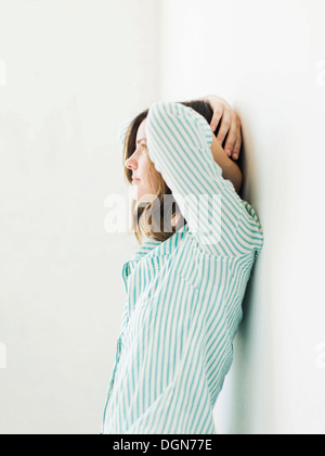Junge Frau, die an die Wand gelehnt Stockfoto