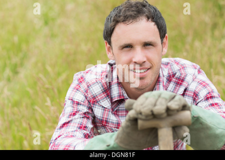 Hübscher junger Mann stützte sich auf seine Schaufel Stockfoto