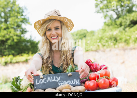 Glückliche junge Bäuerin an ihrem Stand stehen Stockfoto