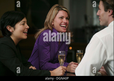 Zwei junge Frauen im Gespräch mit einem Barkeeper, lachen Stockfoto