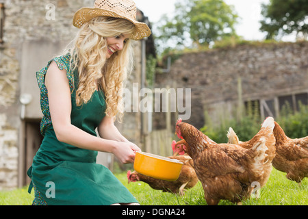 Junge Frau, die ihre Hühner füttern Stockfoto