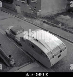 Geschichtsbild, ein Auto und eine ungewöhnliche gebogene geformte Wohnwagen geparkt in einer kleinen Seitenstraße, Frankreich der 1950er Jahre. Stockfoto